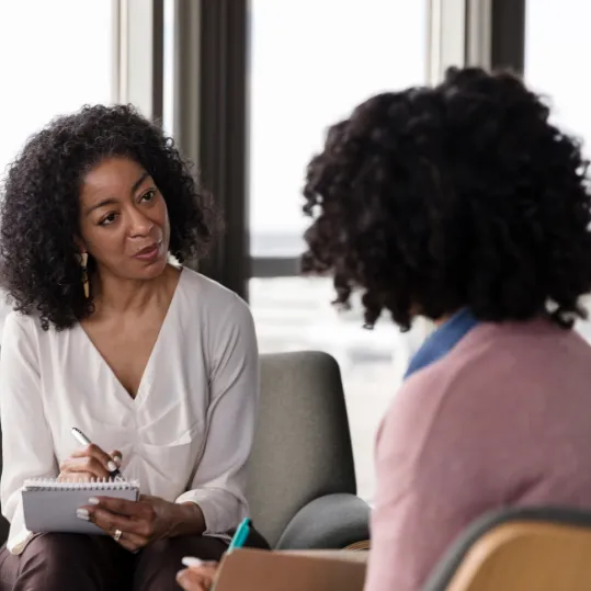 Therapist taking notes while counselling a client, representing psychiatric care, support services, and negligence claims.
